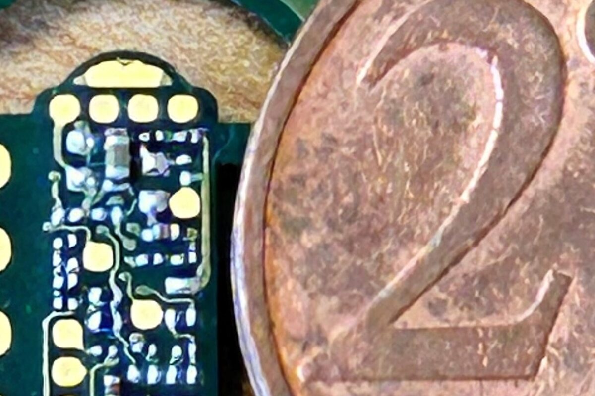 Mikroskopische Ansicht Einer Bestückten Platine Mit 01005 Bauteilen Neben Einer 2 Cent Münze Zum Größenvergleich. Präzise Elektronikfertigung Bei Eps.